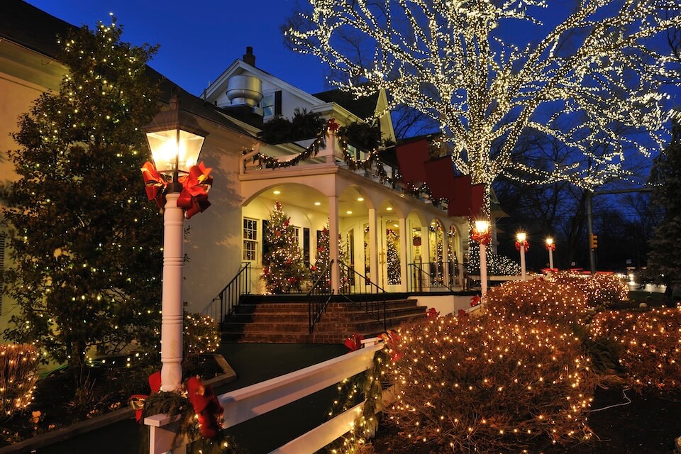Vue d'une maison avec ses arbres et arbustes illuminés pour le temps des Fêtes